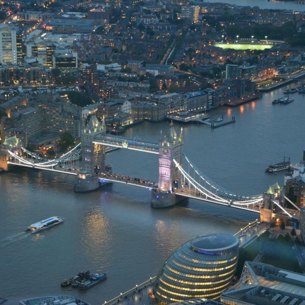 A stunning aerial photograph capturing London's Tower Bridge illuminated at night over the Thames River.